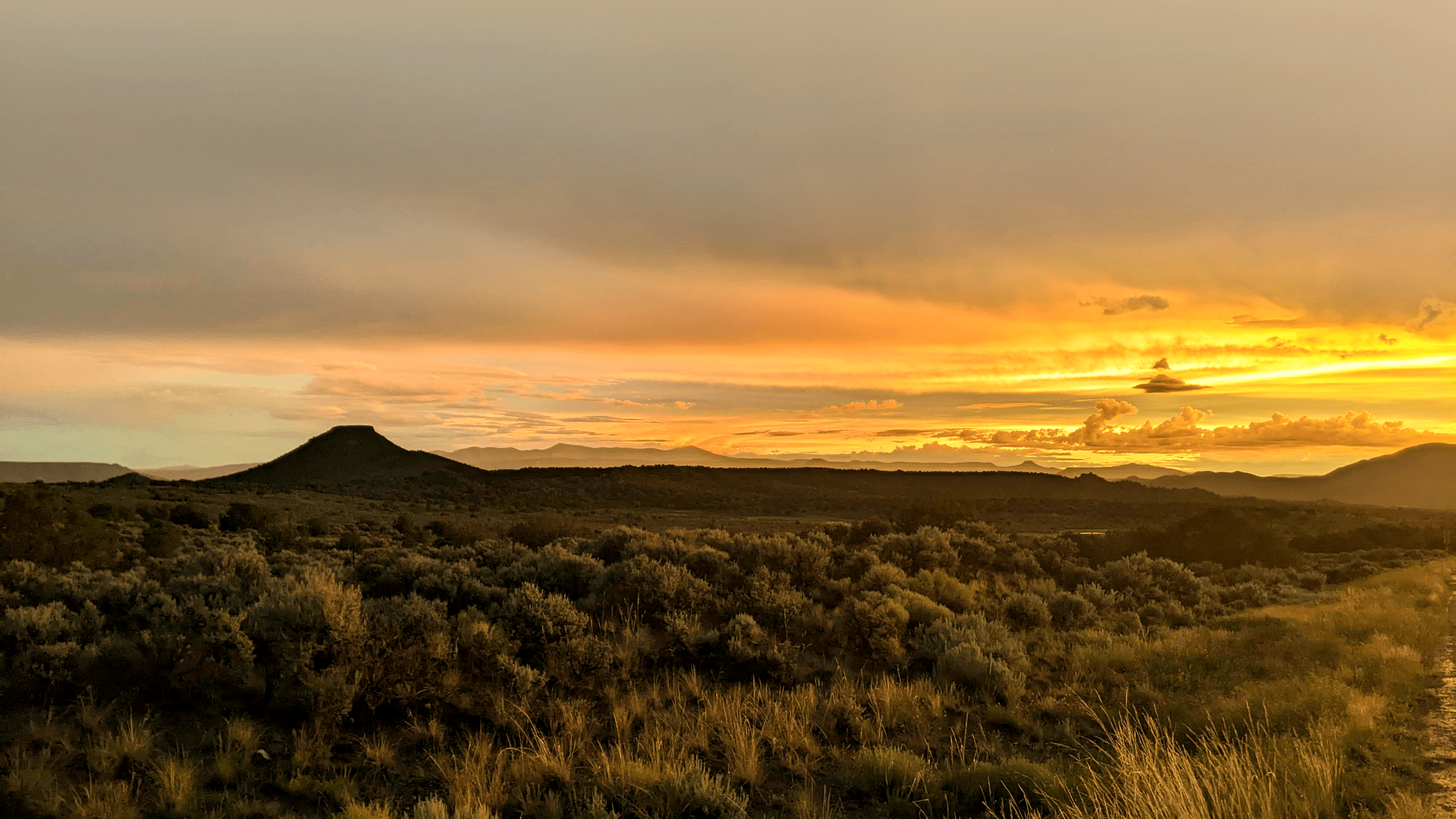 Paisaje desértico al atardecer, con un cerro volcánico en el horizonte — hero de Inicio